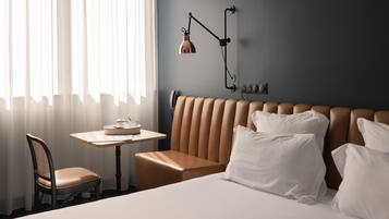 Una habitación de hotel con cama, una mesa, una silla y una lámpara de pared.