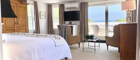 Une chambre d’hôtel avec un grand lit, un bureau avec une chaise, une télévision et une vue sur la mer.