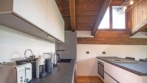 Una cocina moderna con encimera negra, armarios blancos y techo de madera.
