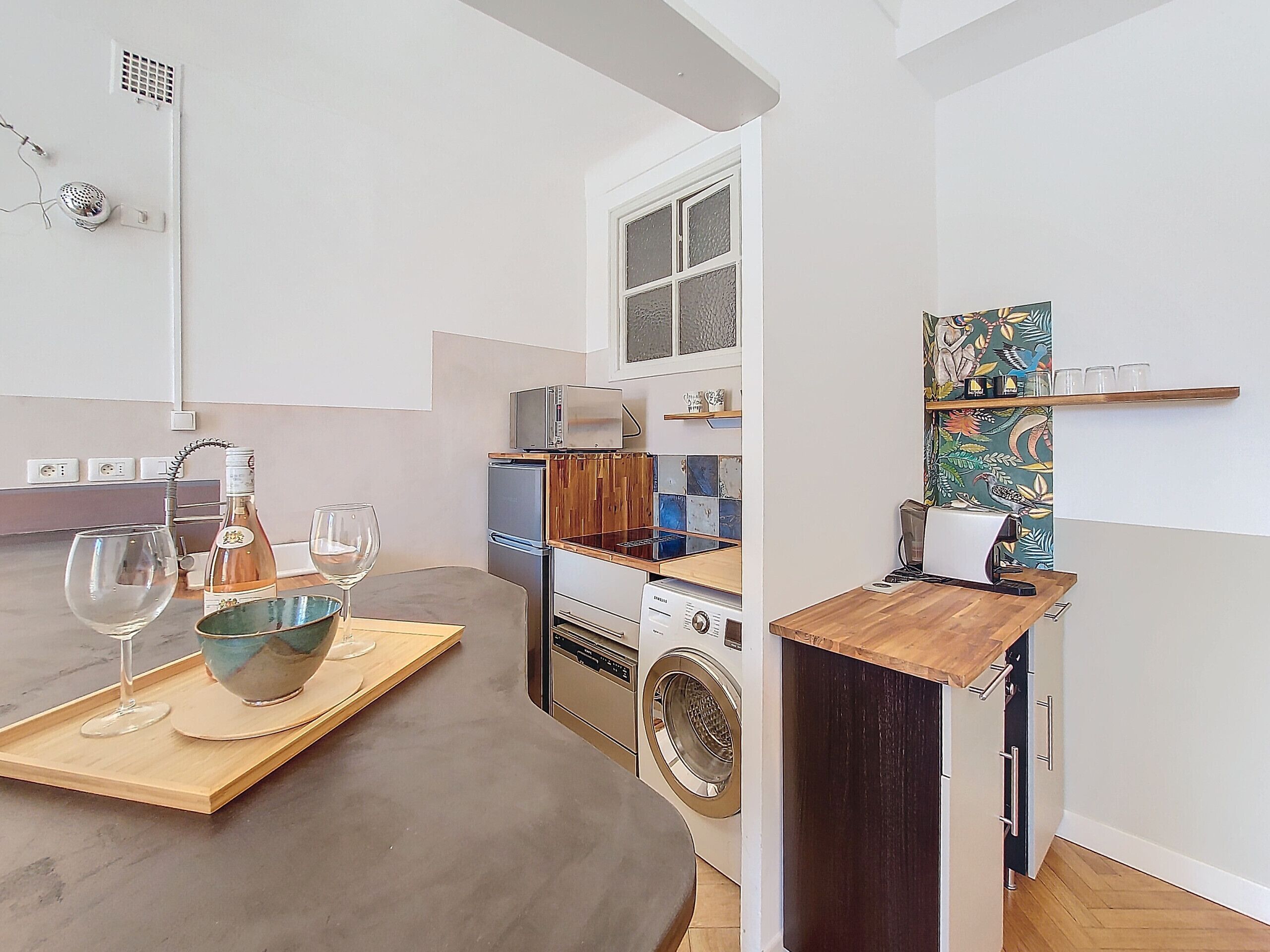 A compact kitchen with a washing machine, a microwave, and a small refrigerator.