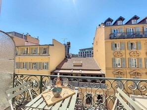 A balcony with a table set for two, featuring a bottle and glasses.