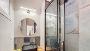 A bathroom with a wooden vanity, a round mirror, and a glass shower enclosure. - N&J - CITY TRIP - Central - Balcony (Niza)