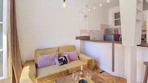 A modern living room with a sofa, a coffee table, and a kitchen area in the background. - N&J - CITY TRIP - Central - Balcony (Niza)