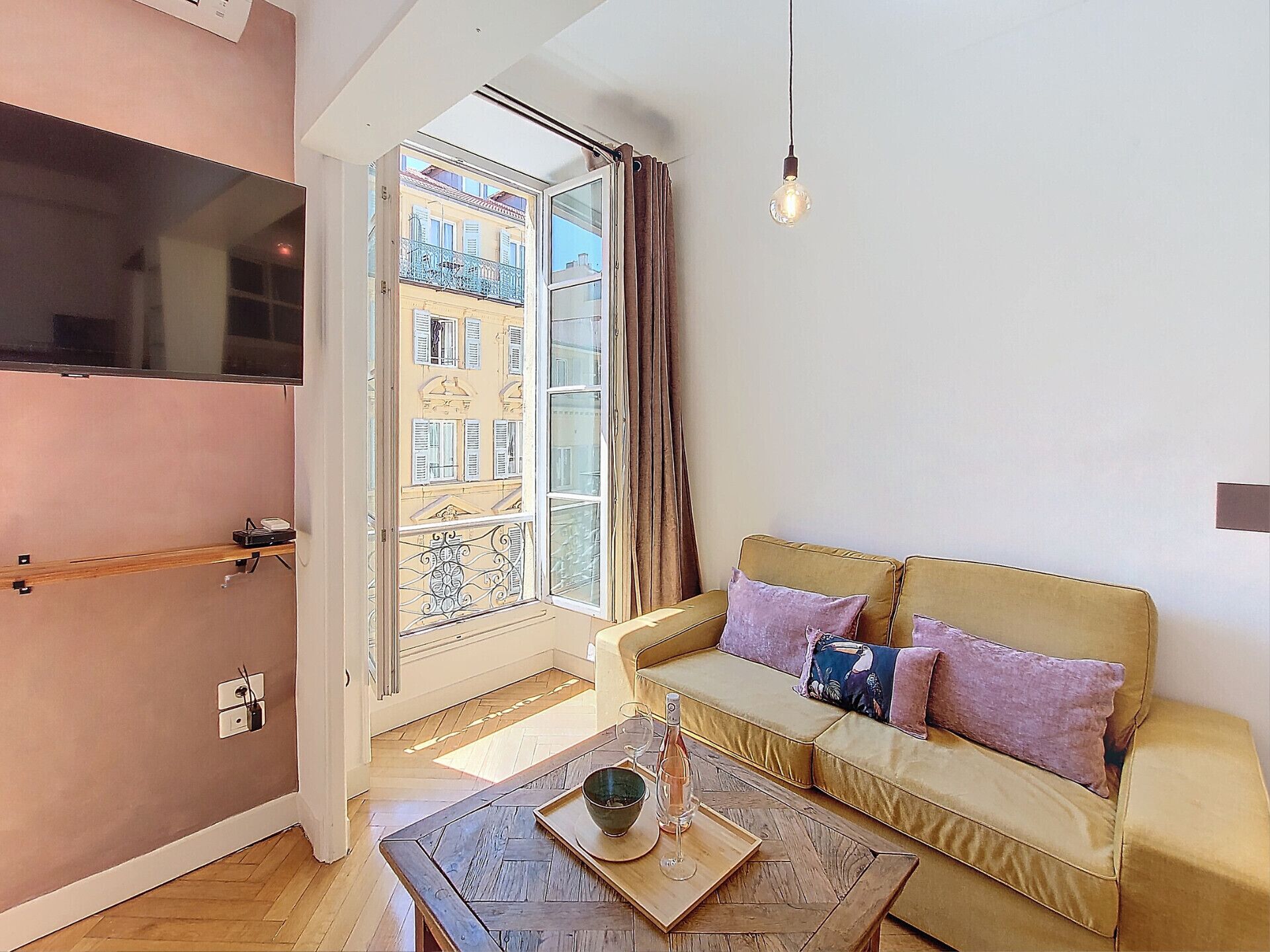 Una sala de estar con un sofá, una mesa de centro y una ventana con vistas a edificios.