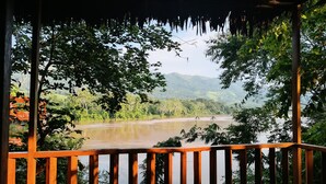 Una terraza de madera con vistas a un río y follaje circundante.