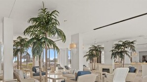 Eine großzügige Lobby mit mehreren Sitzbereichen, üppigen Kübelpflanzen und modernem Design.