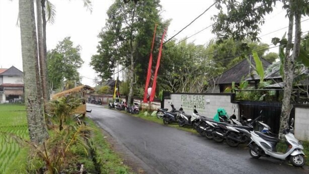 A rural road lined with parked scooters and motorcycles, a sign indicating a property for lease, and a thatched-roof structure. - Duana Sari by Mahaputra (Bali)