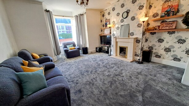 A living room with a sofa, a television, a fireplace, and a patterned wall. - MC Suites (Newcastle-upon-Tyne)