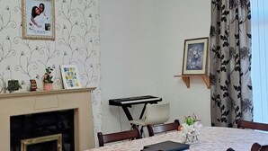 A dining room with a round table, chairs, a chandelier, a fireplace, and framed pictures on the walls. - MC Suites (Newcastle-upon-Tyne)
