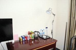 A desk with a lamp, a television, and various beverages. - Yantong Hotel (Nantong)
