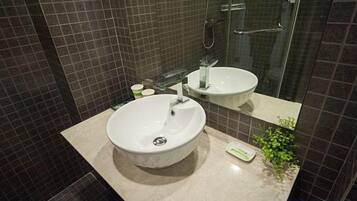 A bathroom with a white sink, a mirror, and a glass shower enclosure.