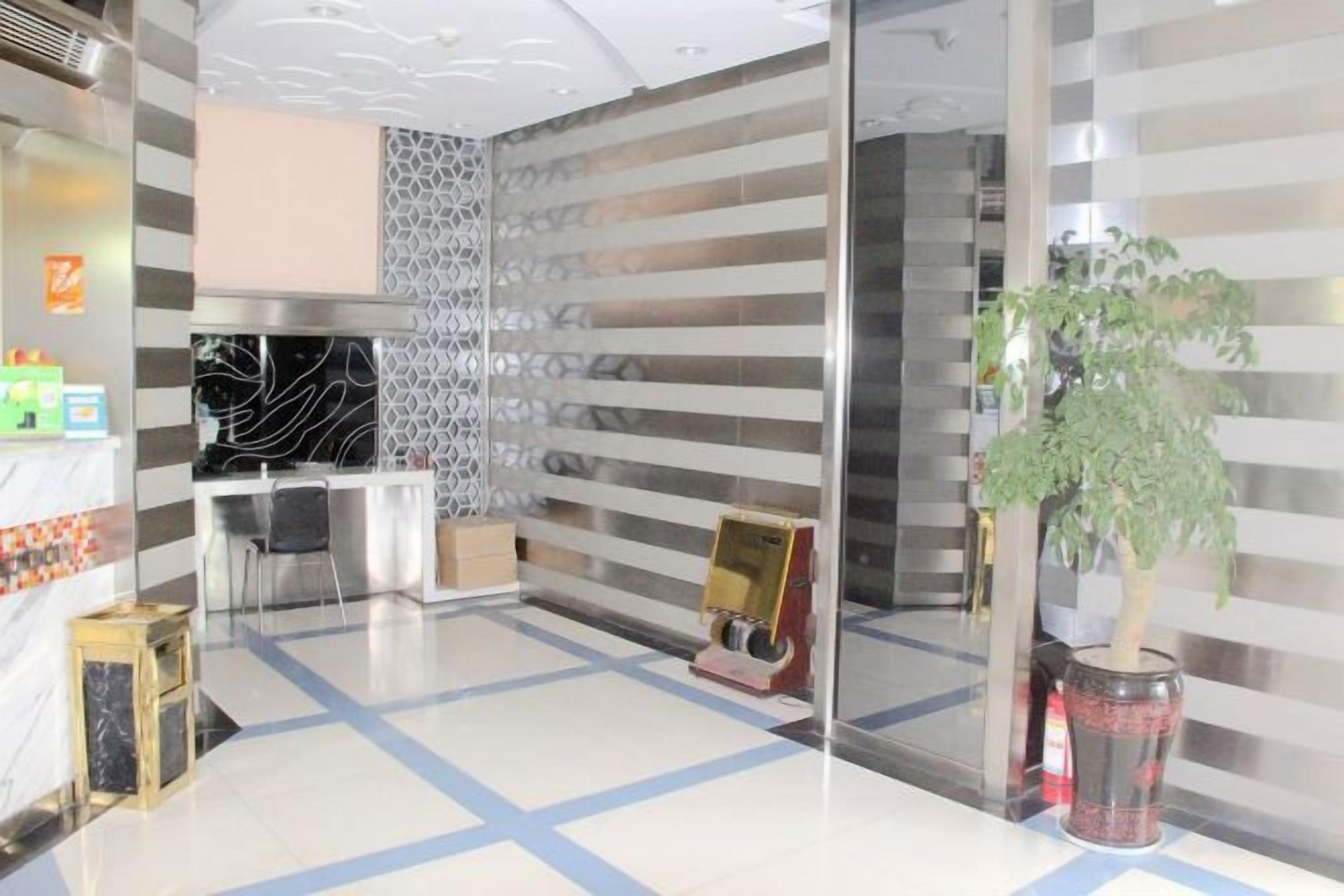 Un área de recepción con mostrador, asientos, un muro decorativo y una planta.
