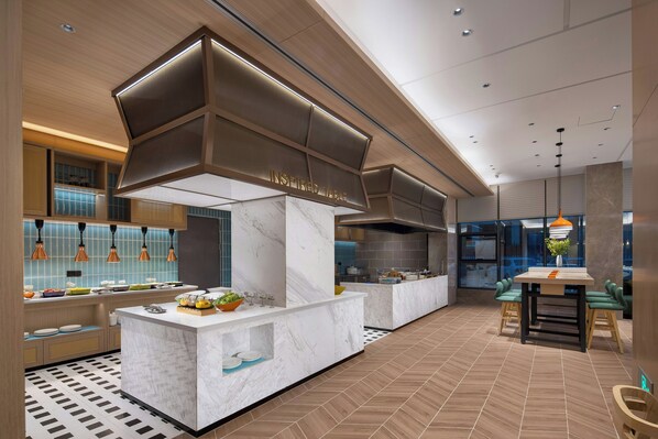 A modern kitchen with marble countertops, a central island, and pendant lighting.