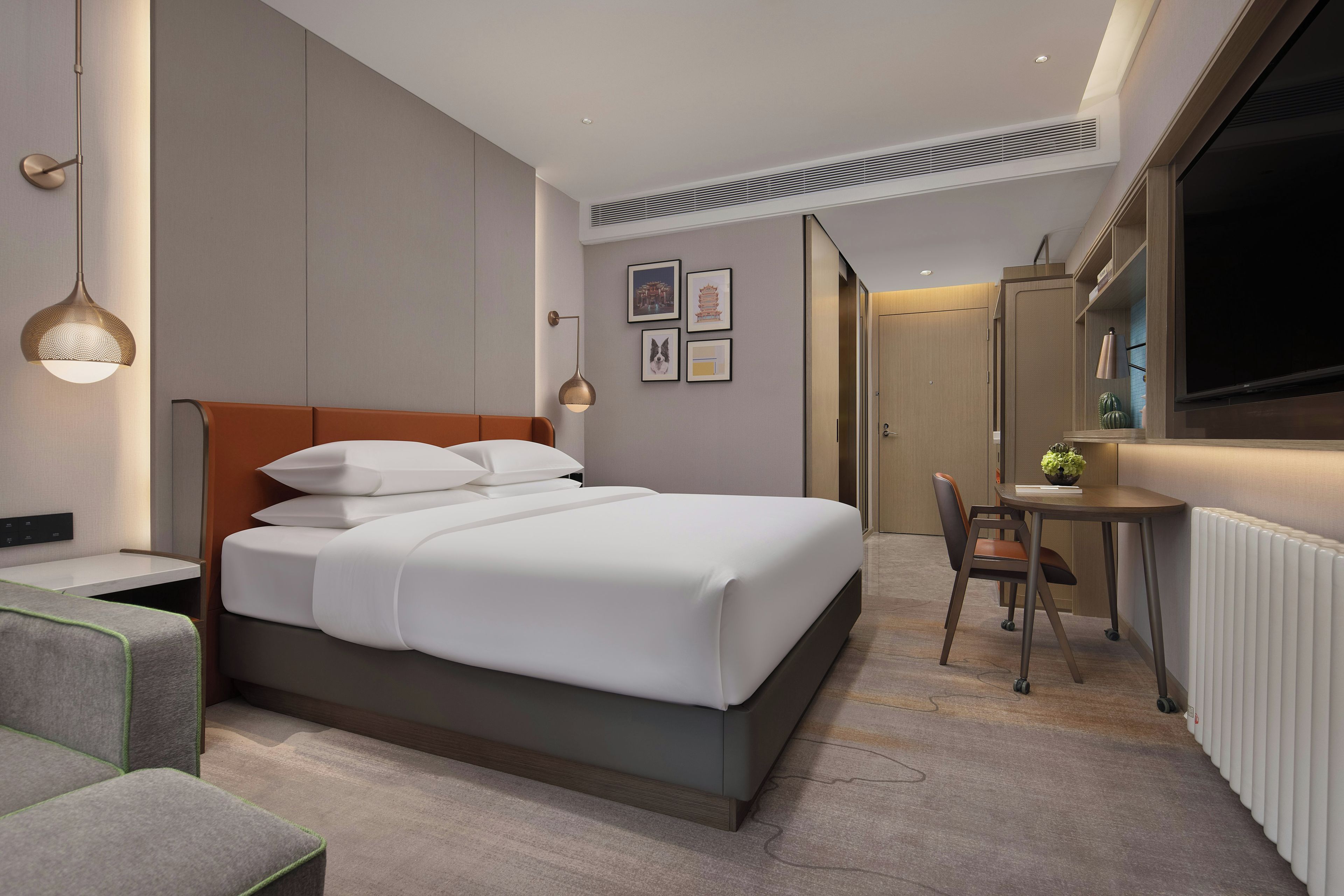 Una habitación de hotel moderna con cama, mesita de noche, silla, escritorio y un ventanal grande.