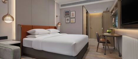 Una habitación de hotel moderna con cama, mesita de noche, silla, escritorio y un ventanal grande.