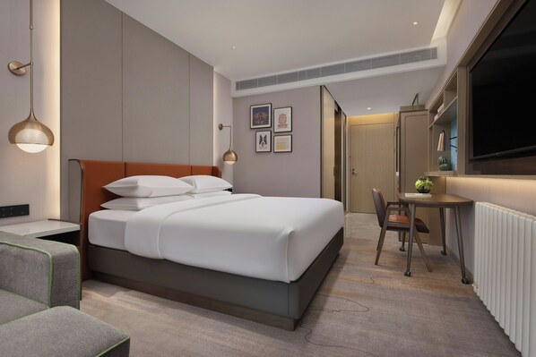 A modern hotel room with a bed, bedside table, chair, desk, and a large window. - Home2 Wuhan Hankou Railway Station (Wuhan)