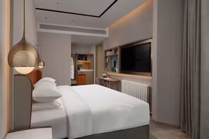 Una habitación de hotel moderna con una cama, televisor, escritorio y ventana.