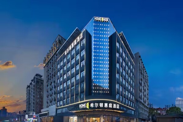 Un hotel de varios pisos con un llamativo letrero 'HOME 2' en la entrada.
