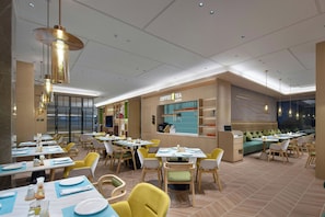 A modern restaurant interior with multiple dining tables, chairs, and a counter area. - Home2 Wuhan Hankou Railway Station (Wuhan)
