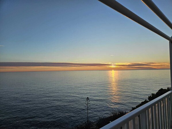 A sunset view from a balcony overlooking a calm sea. - Kates place (Dubrovnik)