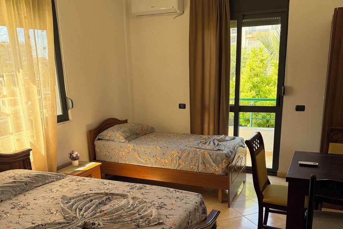 A bedroom with two beds, a desk, and a chair.