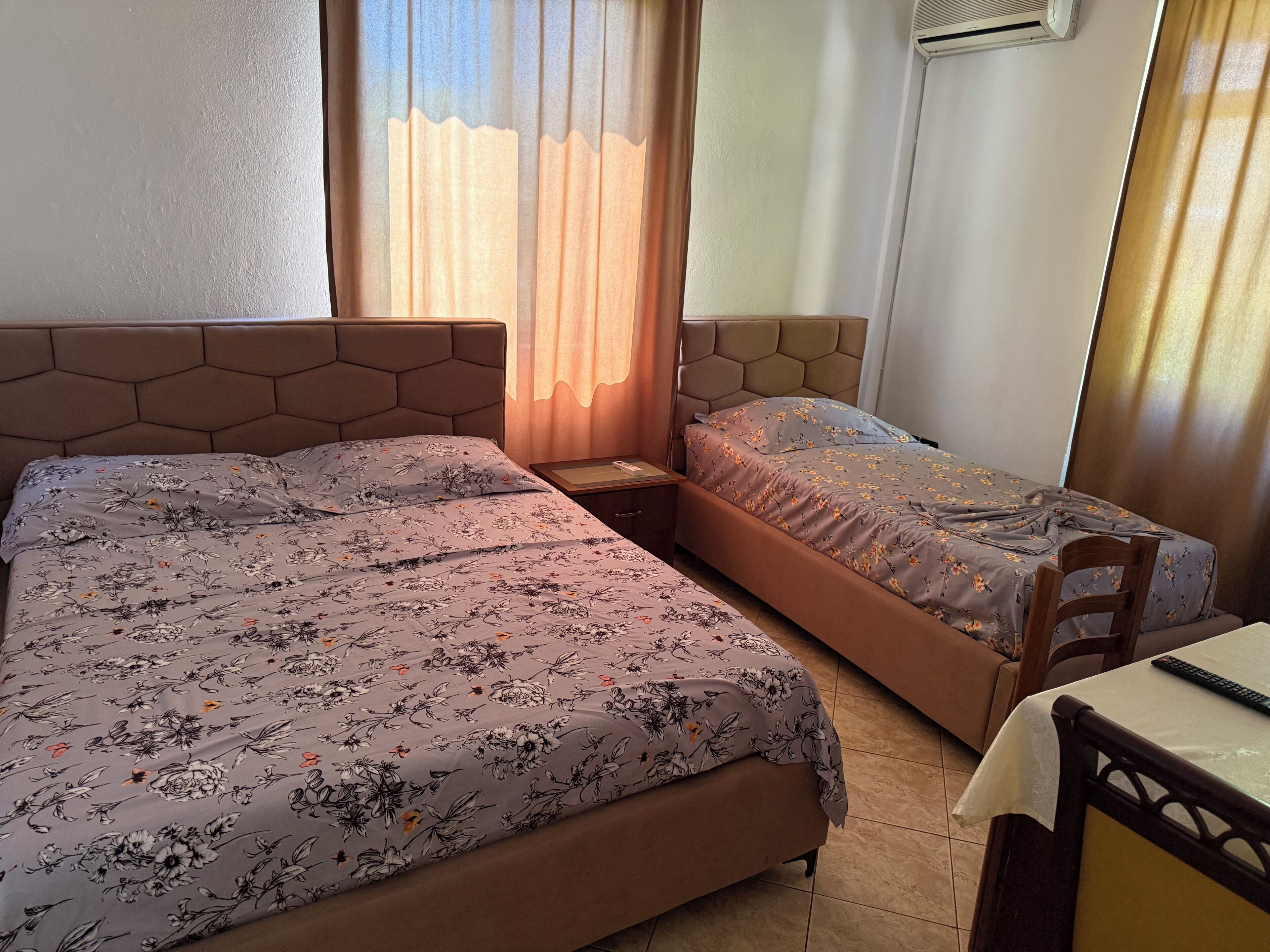 A room with two beds, a small table, and a chair.