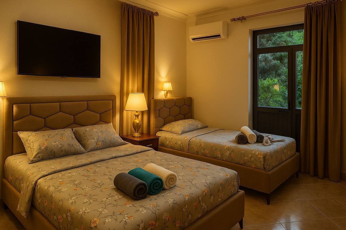 A hotel room with two beds, a flat-screen TV, an air conditioning unit, and a window with curtains.