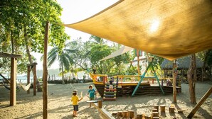 Une aire de jeux de plage avec une structure de jeu en bois et un grand auvent.