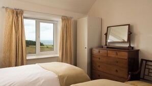 Une chambre avec deux lits, une commode, un miroir et une fenêtre avec des rideaux.
