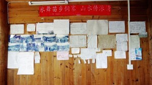 Um quadro de cortiça de madeira com vários papéis fixados, incluindo notas manuscritas e materiais impressos.