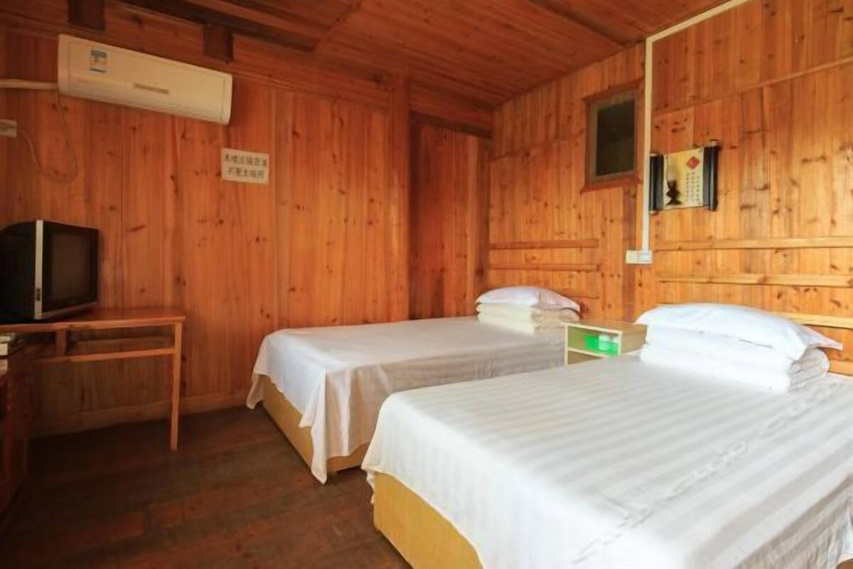 A wooden cabin room with two beds, a television, and a small table.