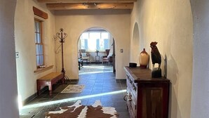 Un couloir avec un plafond en bois, un tapis en peau de vache et une commode ornée d’objets décoratifs.