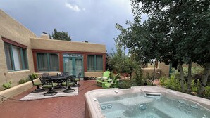 Une terrasse dotée d’un jacuzzi, de mobilier d’extérieur et d’un sol en briques.