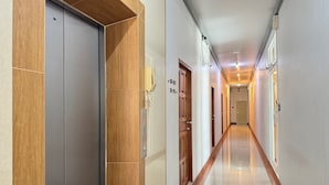 A hotel hallway with a wooden door, a phone, and a sign with room numbers.