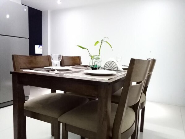 A dining area with a wooden table, four chairs, and a vase with plants.