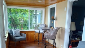 A cozy room with a wooden ceiling, a dining area with a table and chairs, a sofa, and a patterned rug. - Lakeside Retreat with Massage Chair (Lapeer)