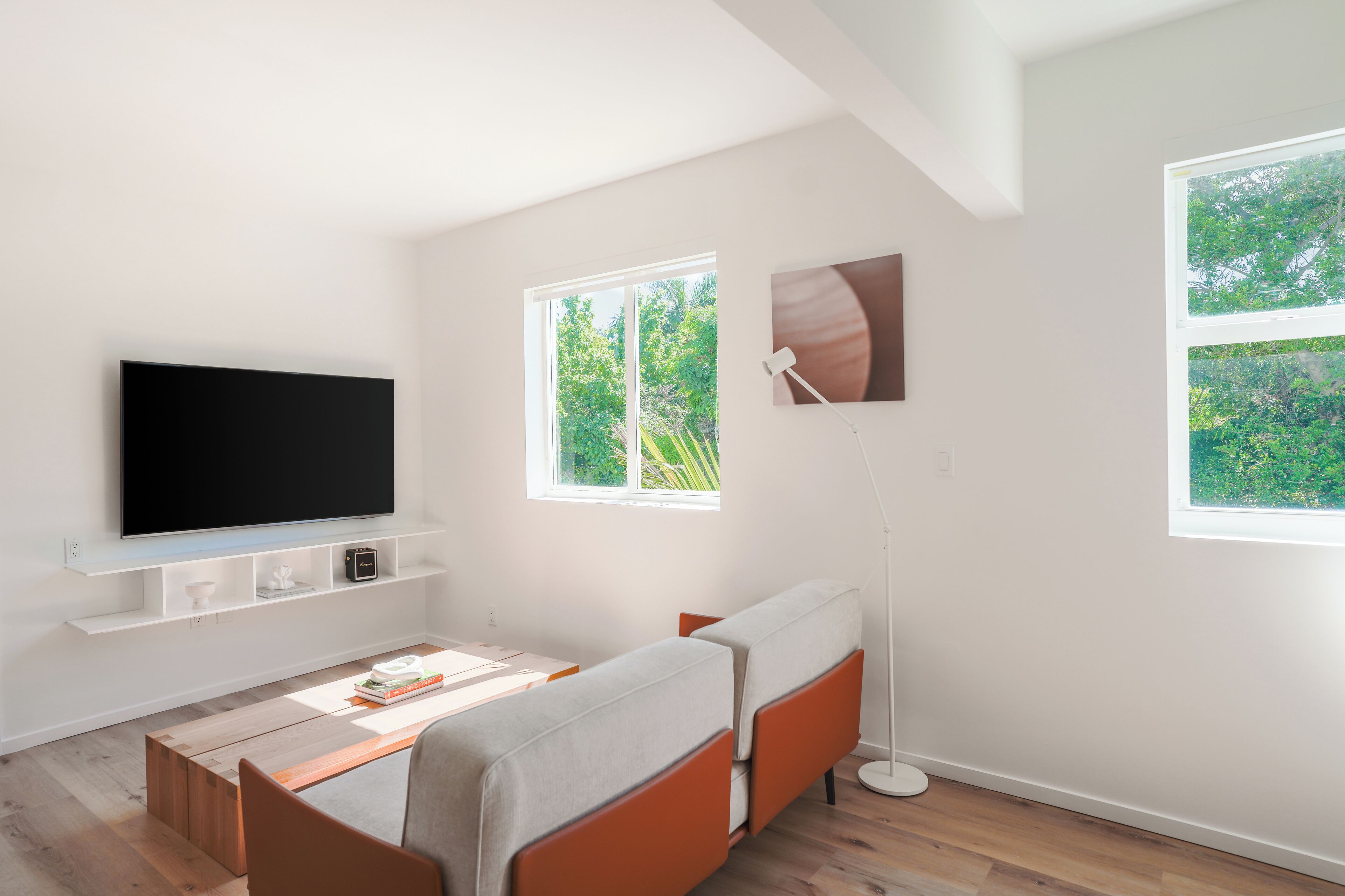 Un salon moderne avec un téléviseur à écran plat, un canapé, une table basse et un lampadaire.
