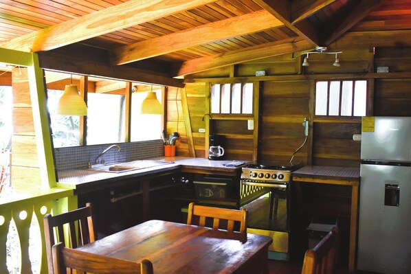 A wooden kitchen with a stove, sink, and refrigerator.