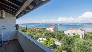 A balcony with a view of a coastal town, a white wall, and a wooden ceiling. - Holiday apartment with air conditioning and sea view (Tkon)