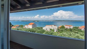 A balcony with a view of a coastal area, including houses and a body of water. - Holiday apartment with air conditioning and sea view (Tkon)
