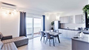 A modern apartment with a dining area, kitchen, and a balcony with a view. - Holiday apartment with air conditioning and sea view (Tkon)