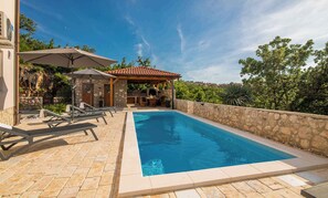 A swimming pool with lounge chairs and a stone wall.
