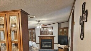 Un salon avec une cheminée, un téléviseur et un grand meuble en bois.