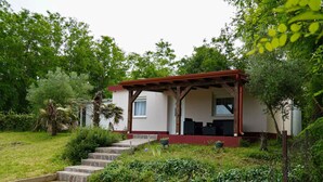 Una casita con porche, escalones de piedra y jardín.