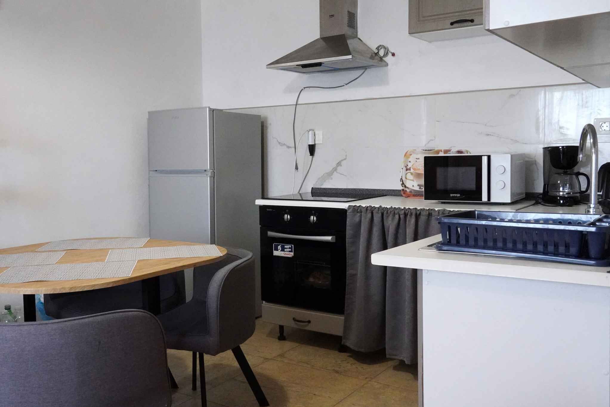 A compact kitchen with a refrigerator, microwave, oven, and a coffee maker.
