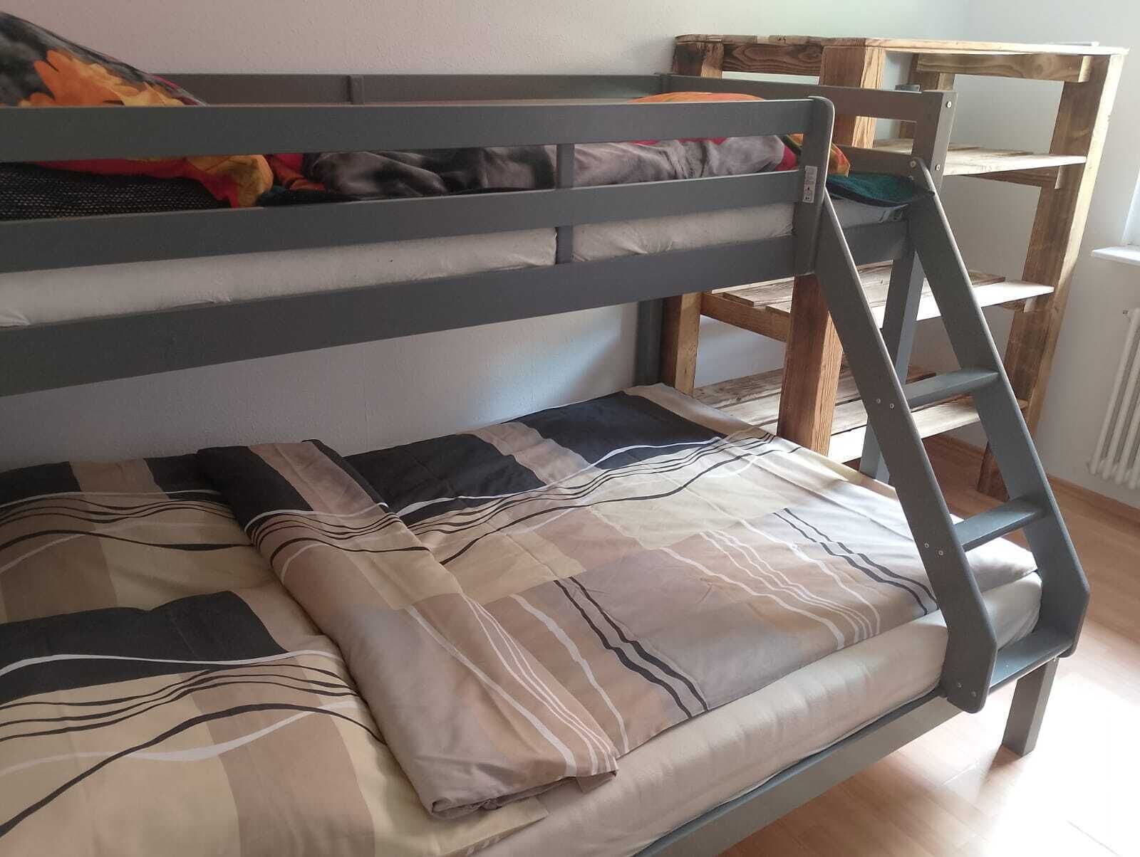 A bunk bed with a ladder, a wooden chair, and a bed with striped bedding.
