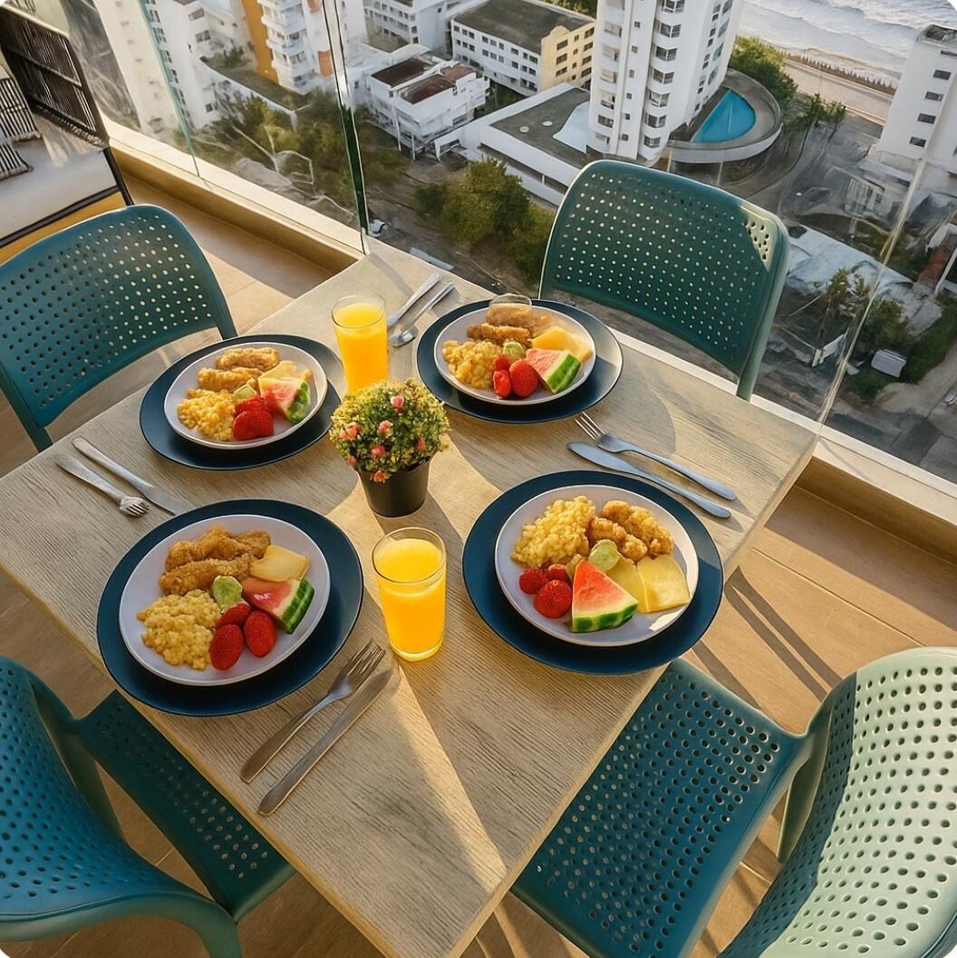 Ein Esstisch mit vier Tellern Essen, zwei Stühlen, einem kleinen Topfpflanzen und einem Glas Orangensaft.