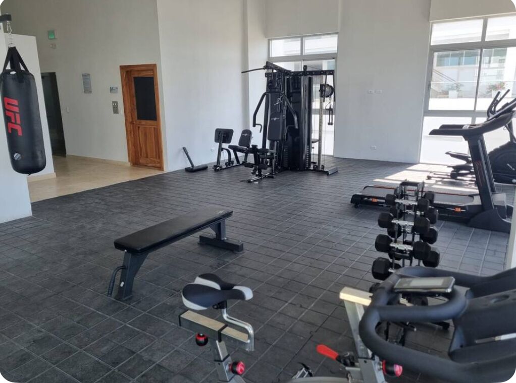 Et fitnessrum med bænk, vægtbænk og træningsudstyr.