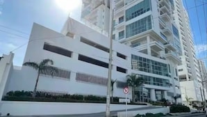 Un edificio moderno de varios pisos con fachada blanca y ventanas grandes.