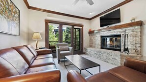 A modern living room with leather sofas, a fireplace, and a television mounted on the wall. - The Charter at Beaver Creek C2305 - Mountain Living (Beaver Creek)